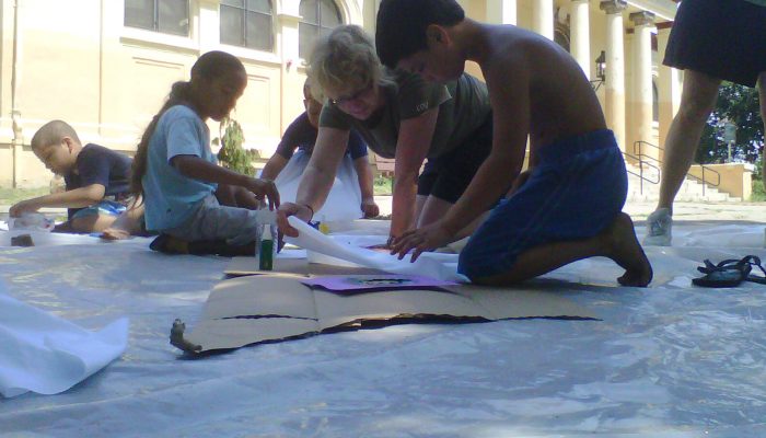 Los niños se arrodillan en el suelo y trabajan en un proyecto artístico.