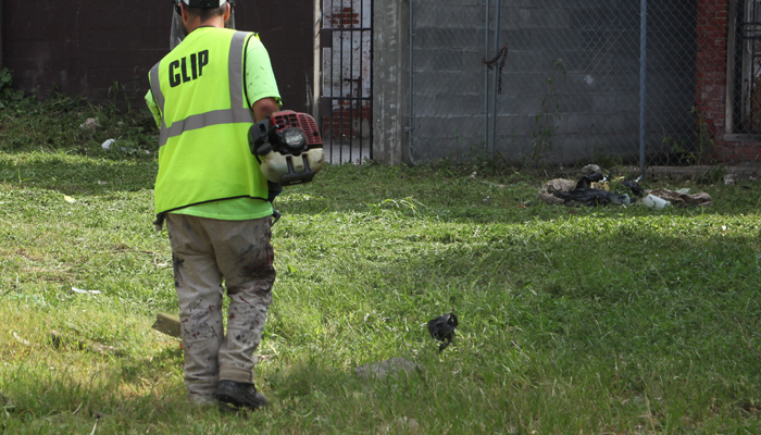 Un trabajador del CLIP maneja una cortadora de pasto en un patio.