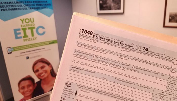 An IRS 1040 tax form, with a banner promoting the Earned Income Tax Credit (EITC) behind it