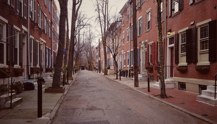 A quiet, tree-lined street in Philadelphia with rowhomes on both sides.