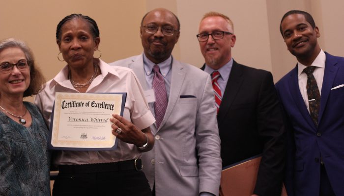 A group of people pose with a certificate of excellence