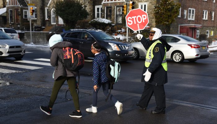 guardia de cruce peatonal ayudando a los niños a cruzar la calle
