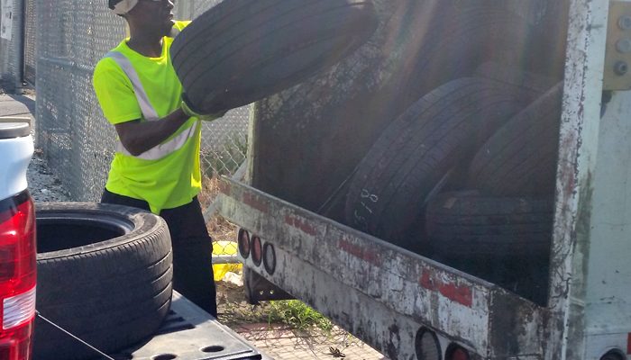 Un hombre pone un neumático en la parte trasera de un camión de la basura