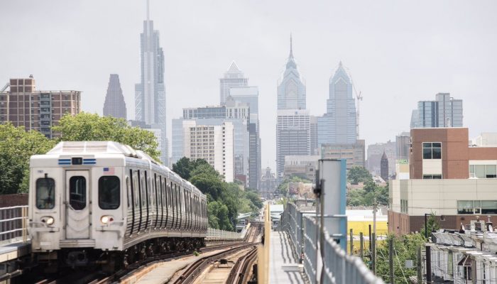 一辆宾夕法尼亚州东南地区交通局 (SEPTA) 列车正在驶离费城。 背景是费城的天际线。