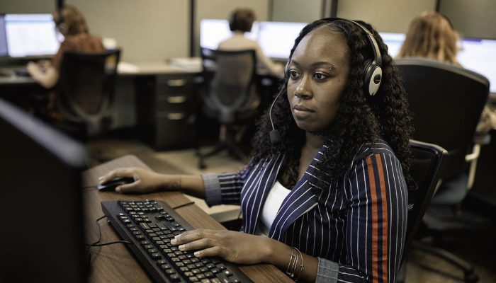 Mujer en un centro de llamadas utilizando auriculares y una computadora de escritorio.