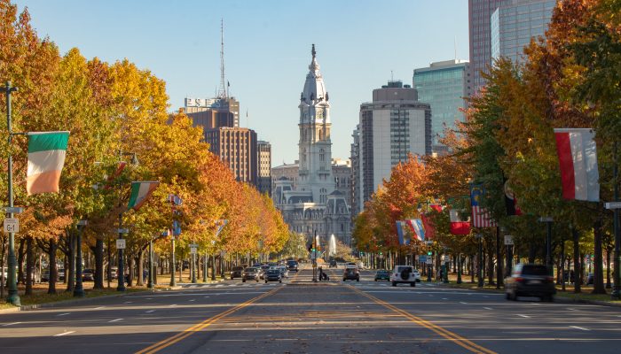 从本-富兰克林公园路的有利位置映出费城市政厅的背景，街道两旁是秋叶景色