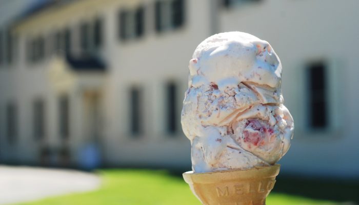 An ice cream cone in the foreground with a building in the background