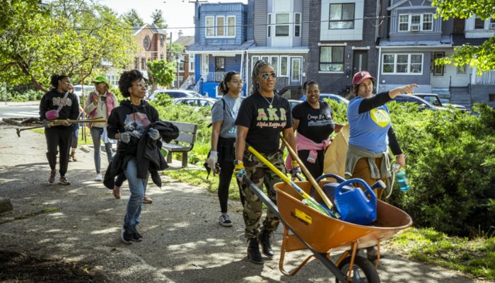 A group of women walking to a park with gardening supplies, mulch, and tools.