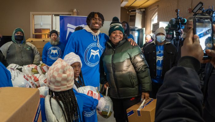 A man and a woman pose for a photo while holding donated food.