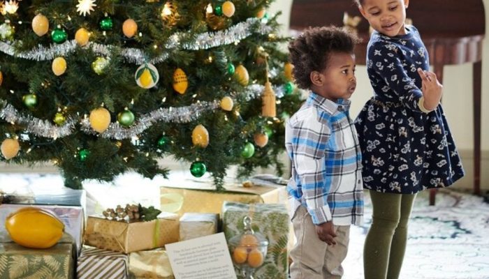 Two children watching a festive performance during a holiday tour, with decorations and holiday lights in the background.