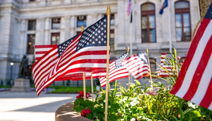 Picture of American flags in in a flowerbed at City Hall's courtyard