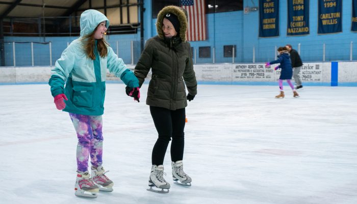 Dos mujeres sonríen y patinan en la pista.