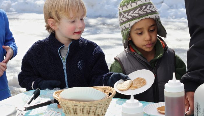 Two young children enjoy fresh maple syrup.