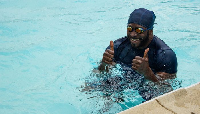 A man gives a thumbs up in a swimming pool.