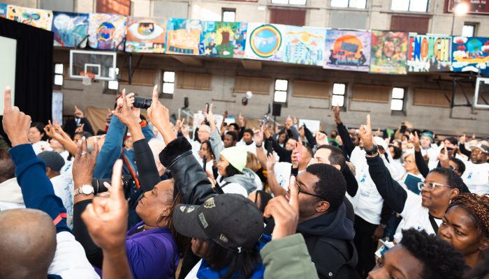 Attendees at the MLK Day of Service at Girard College put their hands in the air, pointing to the ceiling to signify "One Philadelphia"