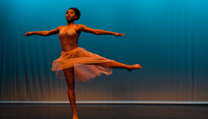 A young woman in ballet attire performs on stage.