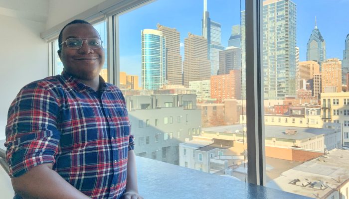 Picture of Edward Stevens by a window of the Philadelphia skyline.